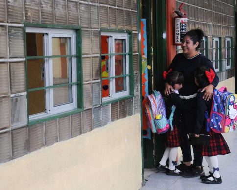 Una madre acompaña a sus dos hijas que se resisten a entrar a su nuevo salón de clases.