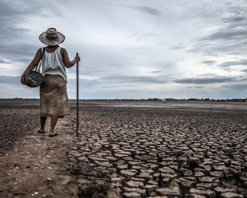 Women standing on dry soil and fishing gear, global warming and water crisis