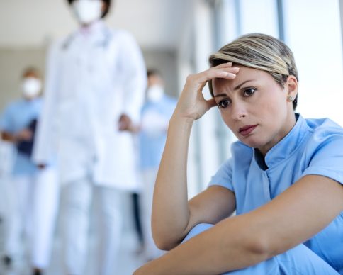 Worried nurse taking a break and contemplating while sitting in a lobby at medical clinic.