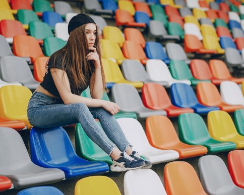 beautiful girl sitting on the colorful chairs  at the stadium