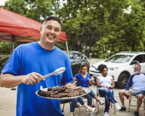 Man handing out burgers at a tailgate party