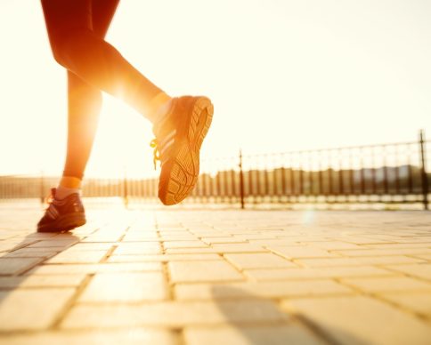 Runner feet running on road closeup on shoe. woman fitness sunrise jog workout welness concept.