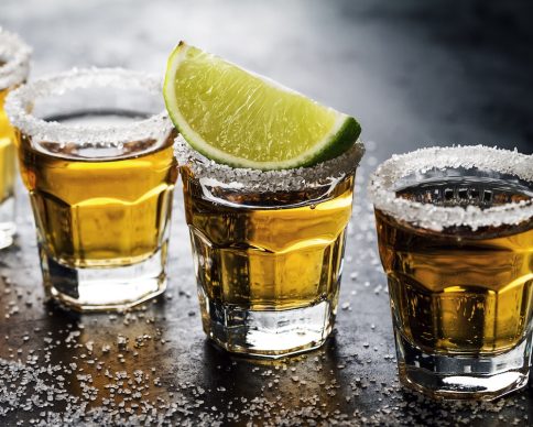 Tasty alcohol drink cocktail tequila with lime and salt on vibrant dark background. Closeup. Horizontal.