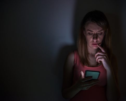 young sad vulnerable girl using mobile phone scared and desperate suffering online abuse cyberbullying being stalked and harassed in teenager cyber bullying concept